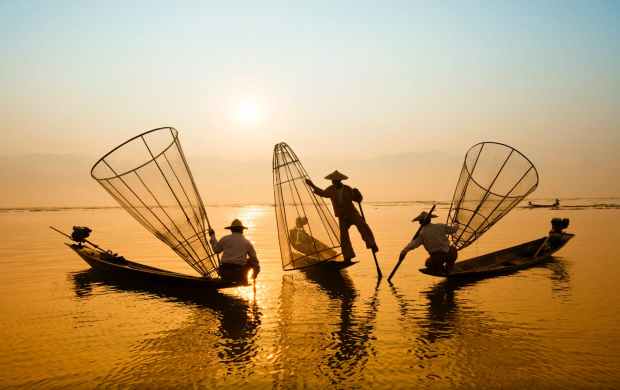 three men riding boats on body of water