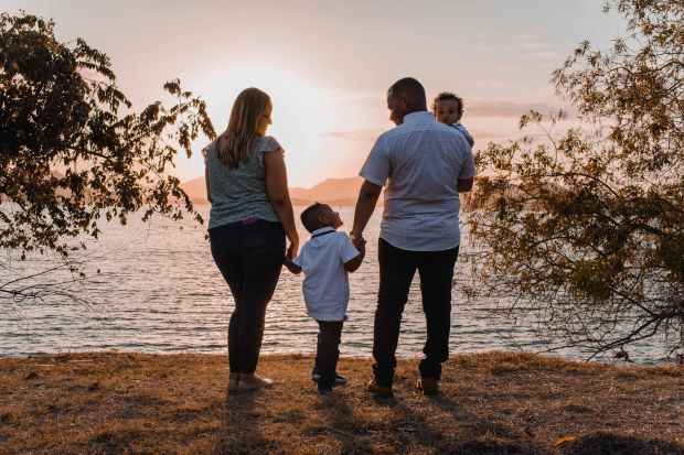 man and woman standing beside body of water during sunset